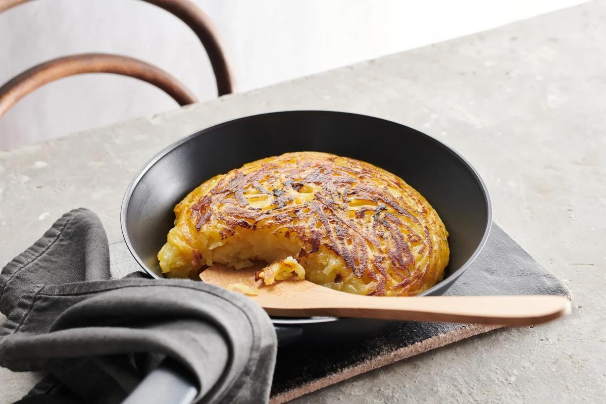 Rösti de pommes de terre crues de la catégorie . Méthode de préparation rôtir. Le plat terminé est joliment présenté et photographié en vue aérienne (photographie alimentaire). Suggestion de présentation, recette originale de Croqu'menus, tirée du livre de cuisine le plus connu de Suisse