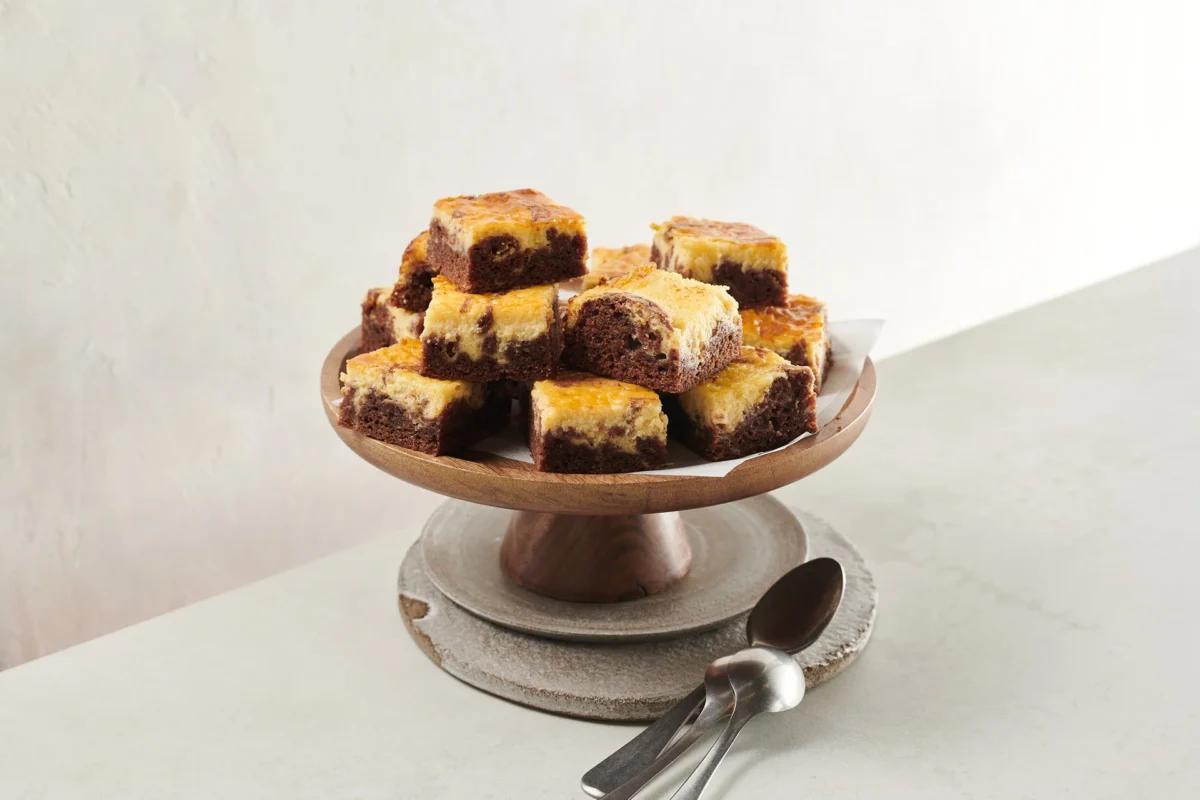 Brownies façon cheesecake de la catégorie . Méthode de préparation cuire. Le plat terminé est joliment présenté et photographié en vue aérienne (photographie alimentaire). Suggestion de présentation, recette originale de Croqu'menus, tirée du livre de cuisine le plus connu de Suisse