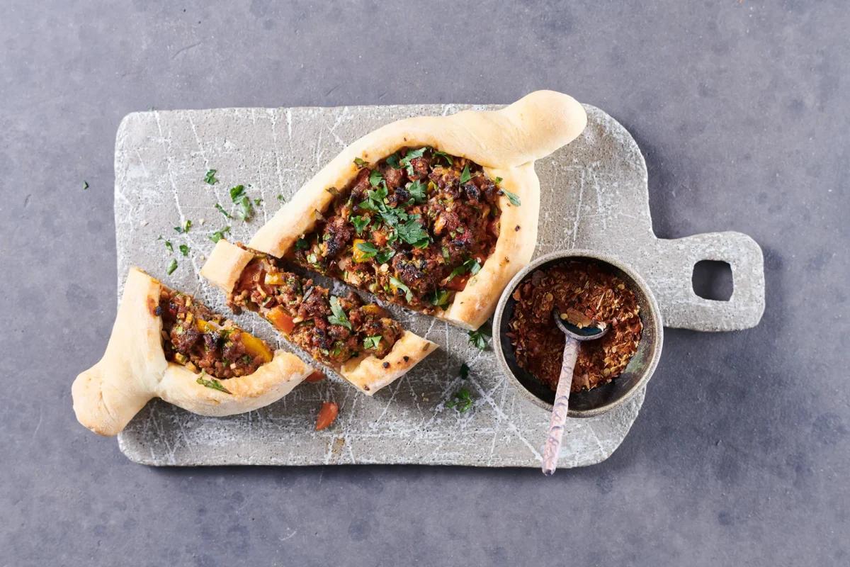 Pide à la viande hachée aus der Kategorie Gebäck salzig. Das fertige Gericht schön angerichtet und fotografiert aus Vogelperspektive (Food Fotografie). Serviervorschlag, Original Tiptopf Rezept, aus dem bekanntesten Kochbuch der Schweiz