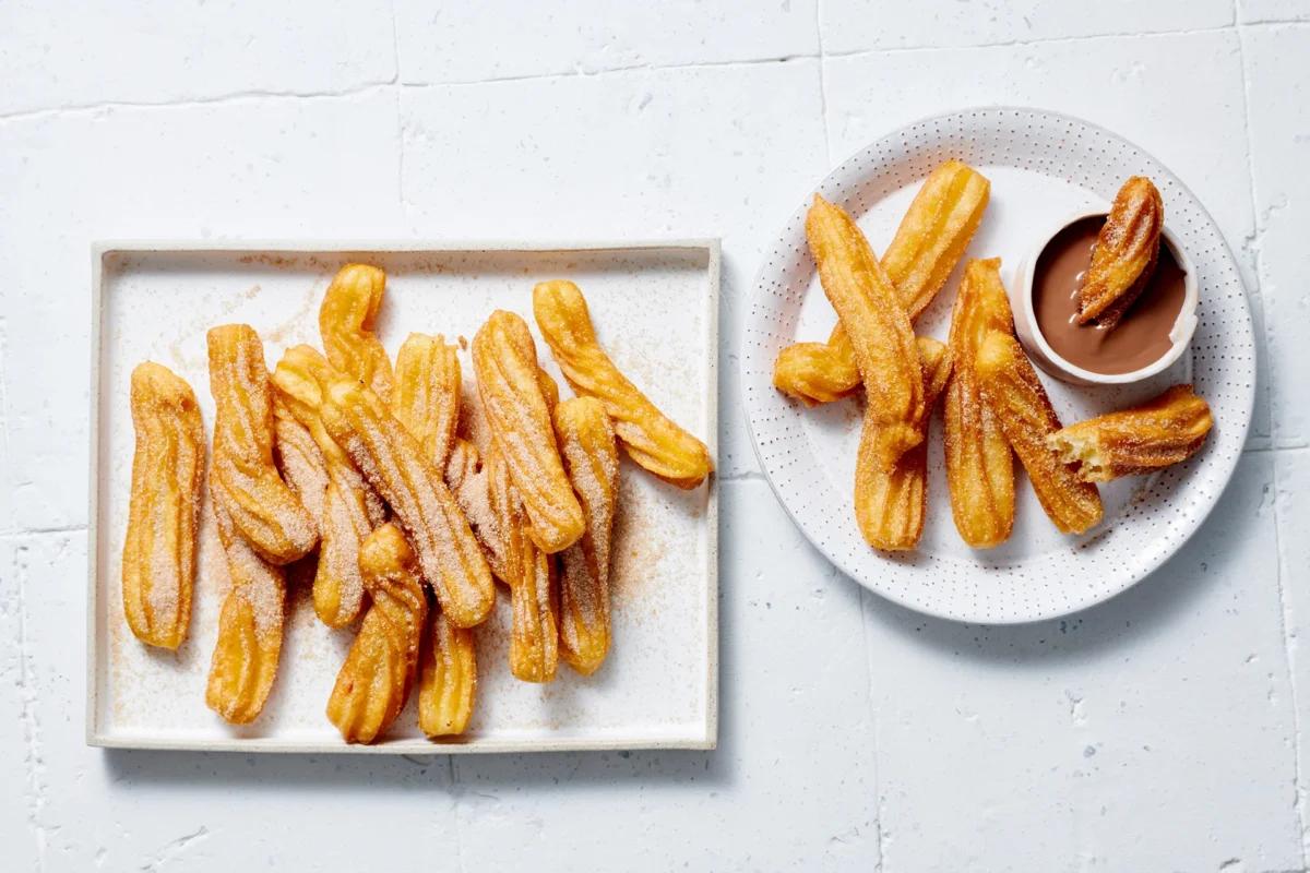 Churros de la catégorie . Méthode de préparation friture. Le plat terminé est joliment présenté et photographié en vue aérienne (photographie alimentaire). Suggestion de présentation, recette originale de Croqu'menus, tirée du livre de cuisine le plus connu de Suisse
