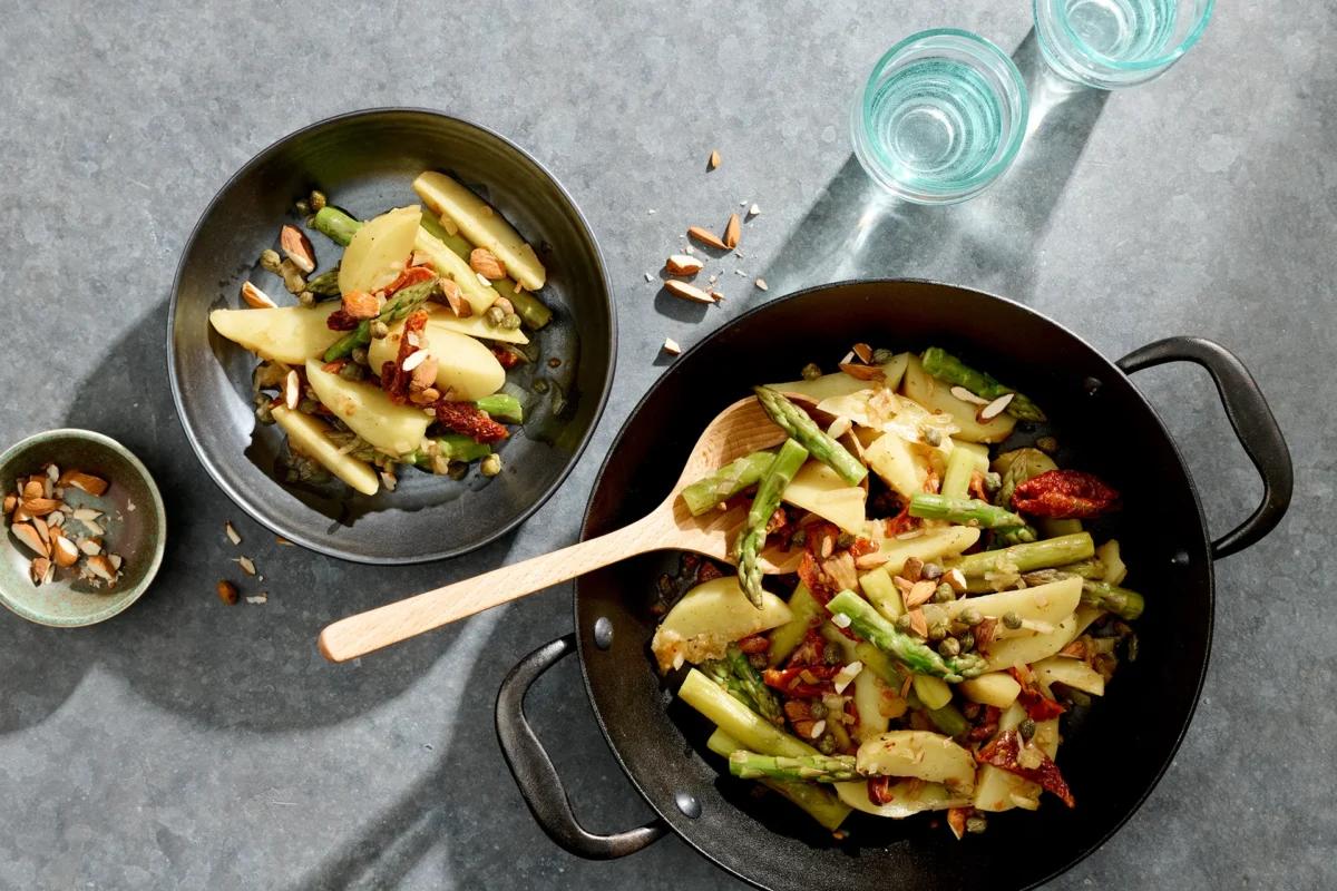 Poêlée d’asperges et de pommes de terre de la catégorie . Méthode de préparation mijoter. Le plat terminé est joliment présenté et photographié en vue aérienne (photographie alimentaire). Suggestion de présentation, recette originale de Croqu'menus, tirée du livre de cuisine le plus connu de Suisse